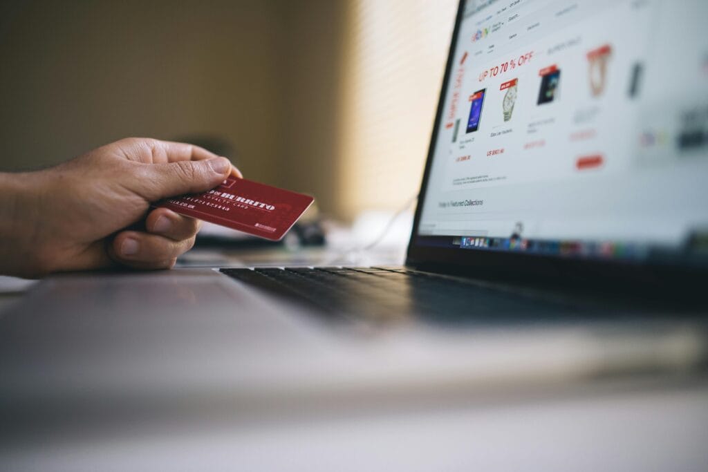 Kuwait Online Grocery Shopping: Overcoming Challenges for a Seamless Experience 4 Person holding a credit card while shopping online on a laptop, indicating ecommerce transactions.